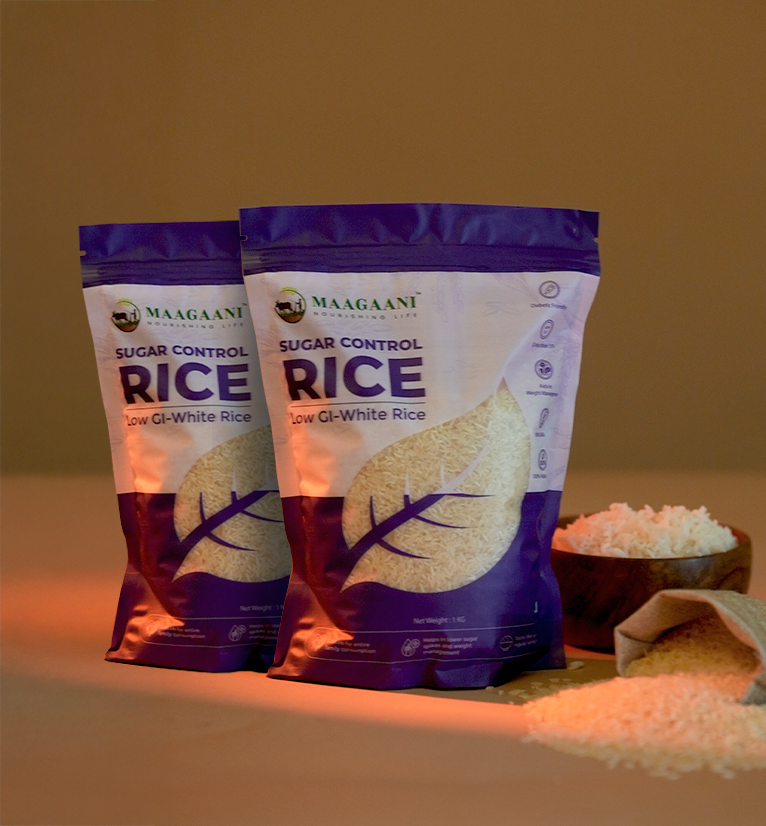 Two Maagaani Sugar Control Low GI White Rice packs displayed beside a wooden bowl of cooked rice and scattered raw grains.